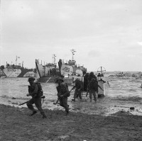Men of 47 Royal Marine Commando land on Jig Beach from LCAs. The tank landing craft behind them are carrying support from the engineers of 79th Armoured Division. At left a bulldozer is towing a trailer filled with fascines, whilst another waits to exit LCT 858 (Imperial War Museum, B5246)